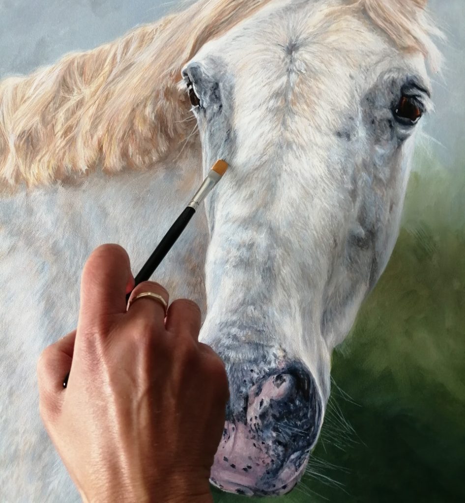 touching up a horse portrait in acrylic with a flat brush