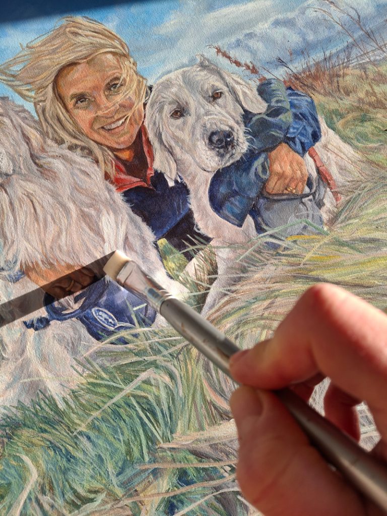 adding detail with a paintbrush to a painting of a woman and two dogs