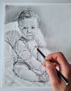 adding detail to a pencil drawing of a baby boy with graphite pencils