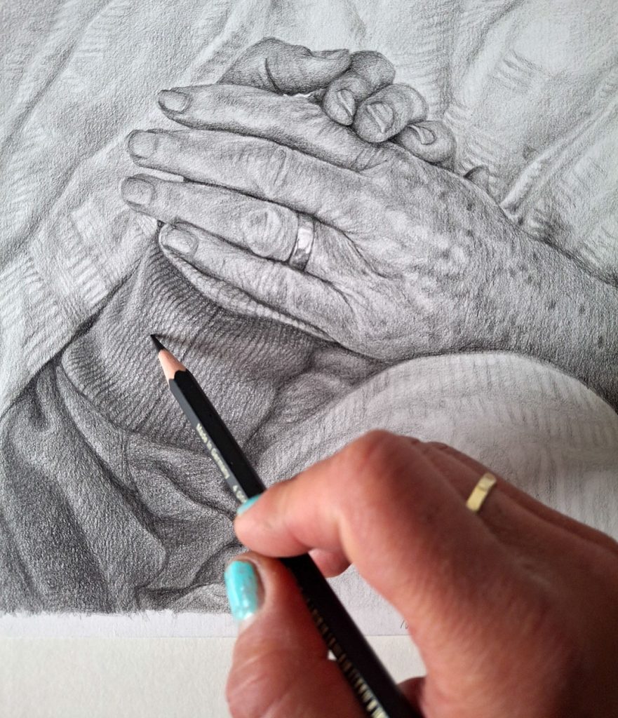 adding detail to a pencil drawing of two hands holding