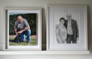 portrait drawing of a couple and painting of a man with dog