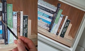 canvas and frame detail of a painting of books on a bookshelf