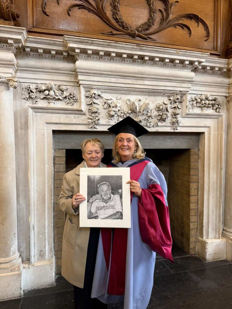 two sisters holding a pencil portrait drawing of their deceased brother during a graduation ceremony