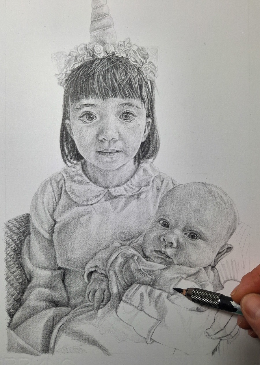 artist hand shading an almost completed portrait drawing of two sisters