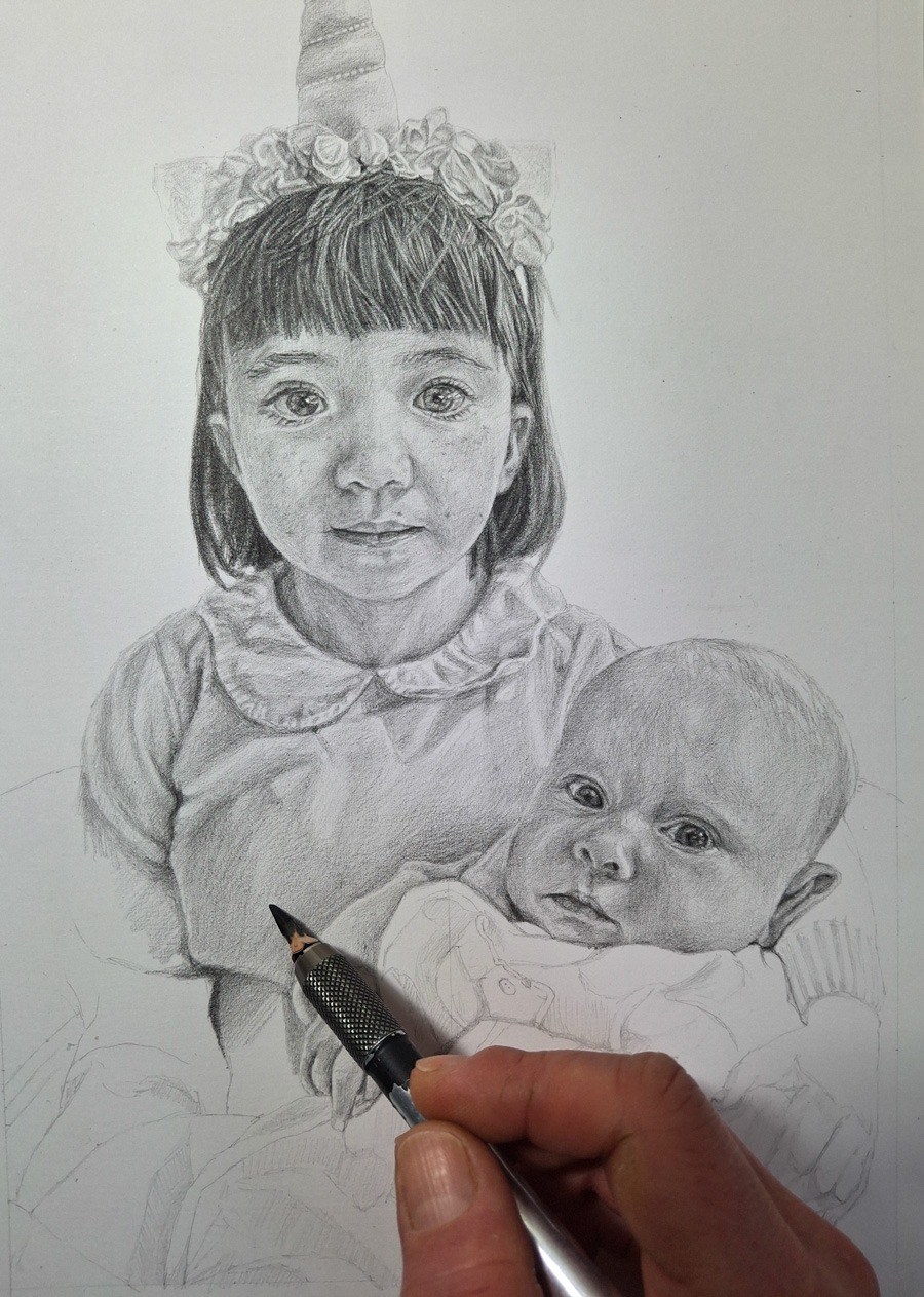 artist hand shading a pencil portrait of two young girls